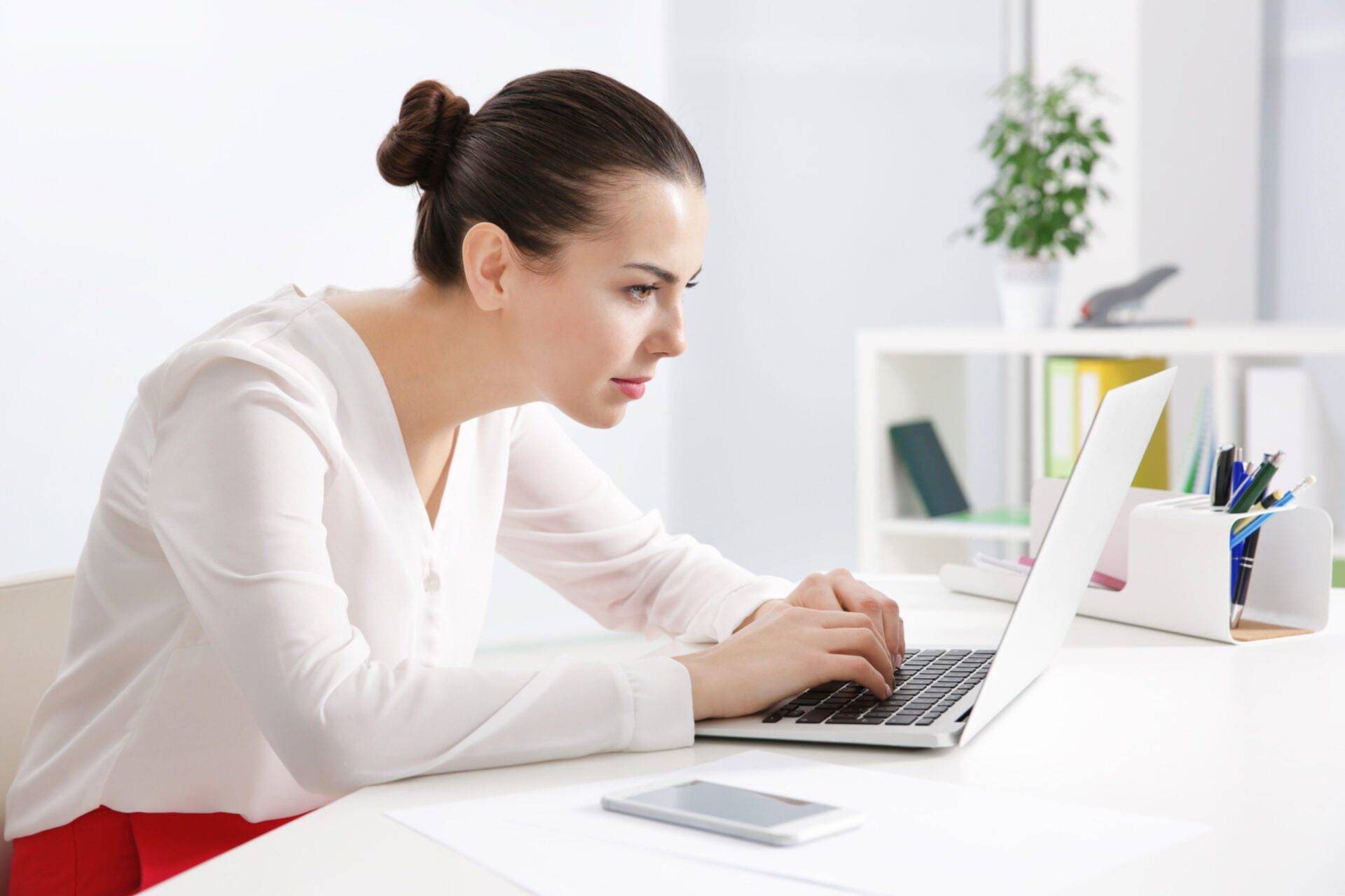 Incorrect posture concept. Young woman sitting at table in modern room