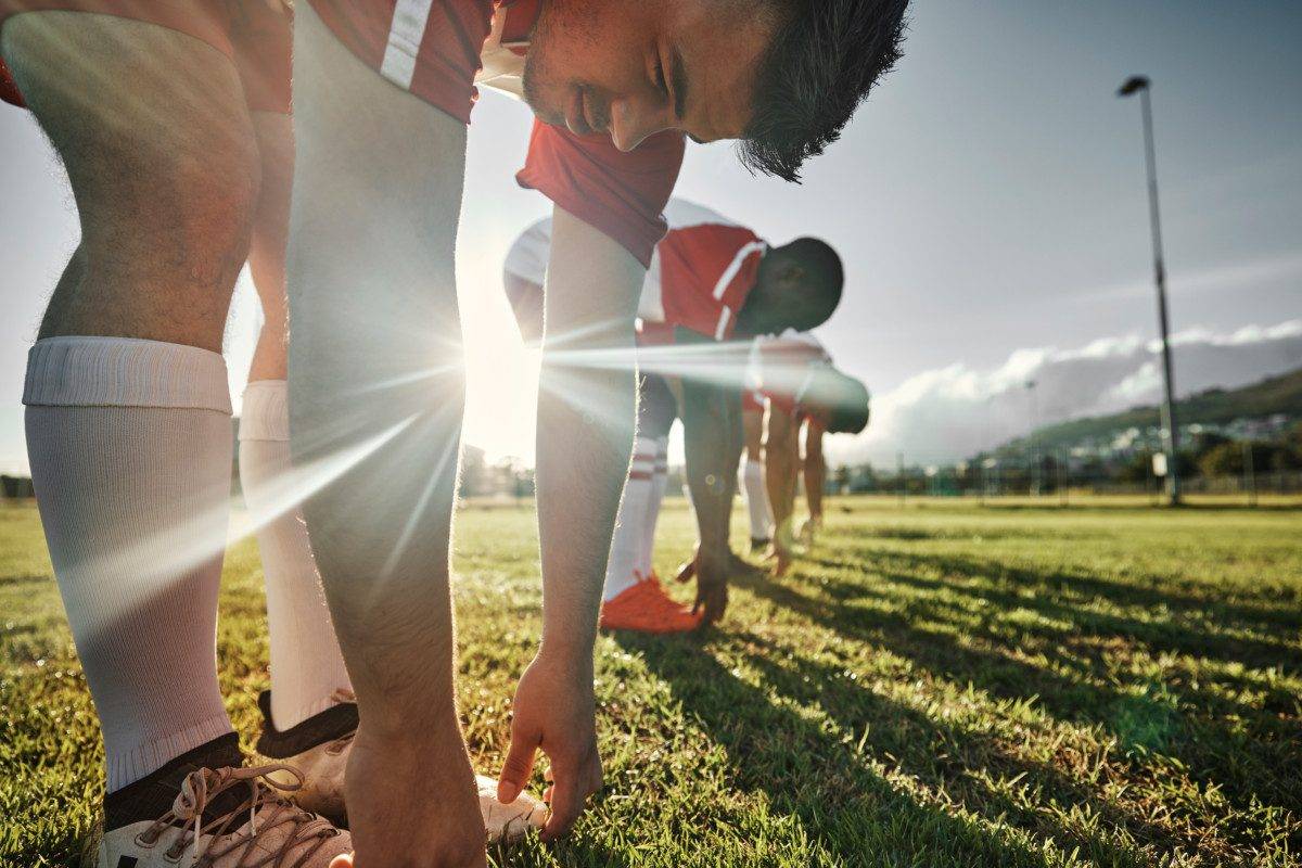 Soccer, sports and team stretching on field before match, training and practice. Soccer players doing fitness, exercise and workout on grass, stretching, performance and ready to start football game