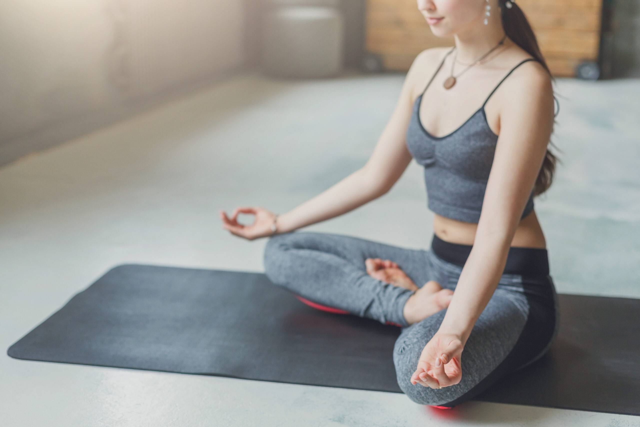 Young woman in yoga class, meditation exercises. Girl does lotus pose for relaxation, crop. Healthy lifestyle in fitness club